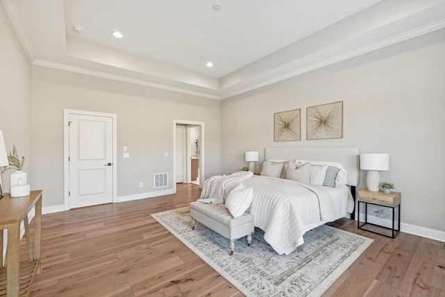 bedroom with a raised ceiling and wood-type flooring