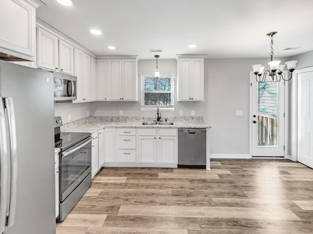 kitchen with decorative light fixtures, a notable chandelier, white cabinetry, appliances with stainless steel finishes, and sink