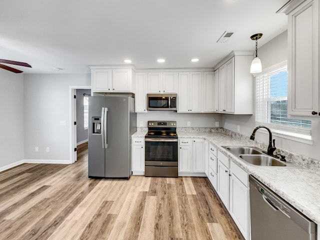 kitchen with decorative light fixtures, stainless steel appliances, white cabinetry, ceiling fan, and sink