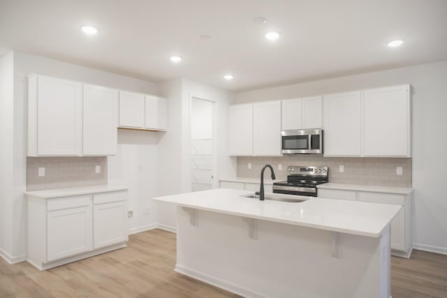 kitchen featuring appliances with stainless steel finishes, white cabinetry, a center island with sink, and sink