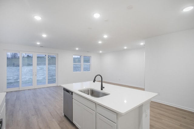 kitchen featuring white cabinets, dishwasher, an island with sink, light wood-type flooring, and sink