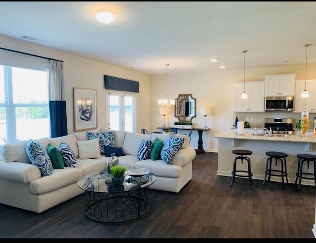 living room with sink, a chandelier, and dark hardwood / wood-style floors