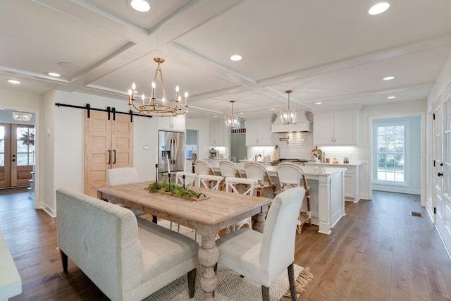 dining area featuring dark hardwood / wood-style flooring, coffered ceiling, a barn door, and beamed ceiling