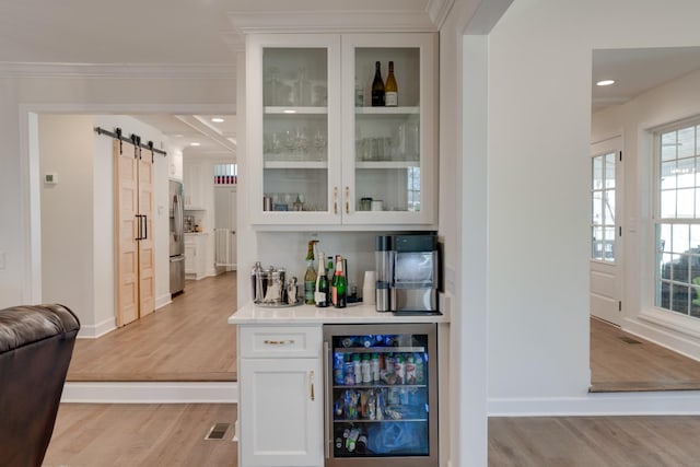 bar with a barn door, stainless steel refrigerator, wine cooler, light wood-type flooring, and white cabinets