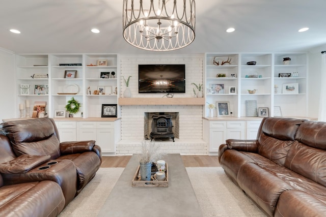 living room featuring built in shelves, light wood-type flooring, a wood stove, and an inviting chandelier