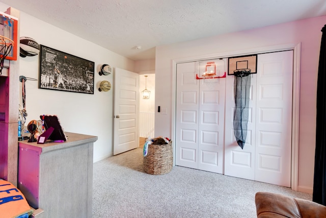 carpeted bedroom featuring a textured ceiling and a closet