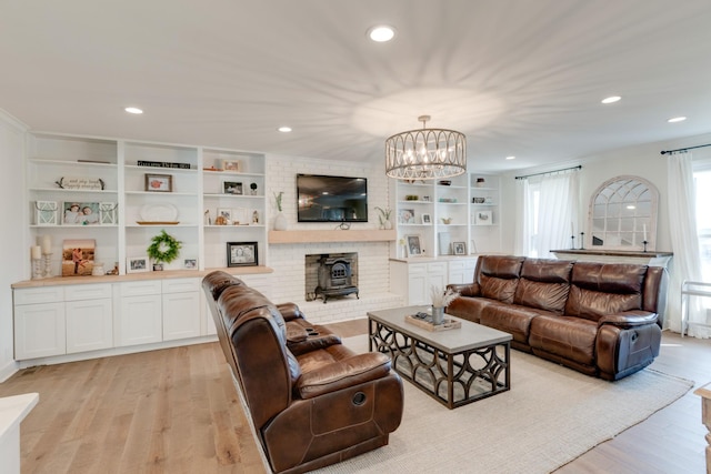 living room with a chandelier, a wood stove, and light hardwood / wood-style flooring