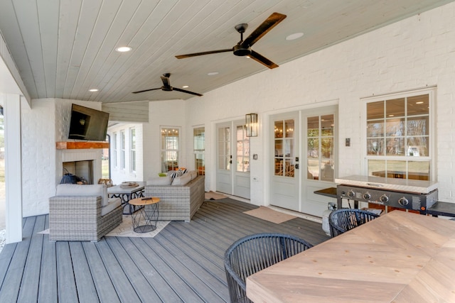 wooden terrace featuring ceiling fan and an outdoor living space with a fireplace