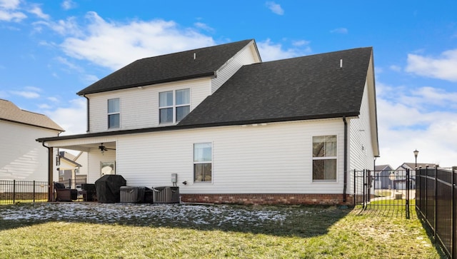 rear view of house featuring ceiling fan and a yard