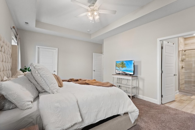 carpeted bedroom featuring ceiling fan, connected bathroom, and a tray ceiling