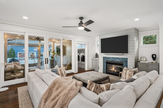 living room featuring a fireplace, ceiling fan, ornamental molding, washer and dryer, and dark hardwood / wood-style flooring