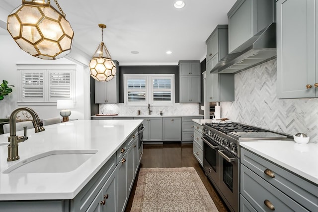 kitchen featuring sink, wall chimney exhaust hood, double oven range, pendant lighting, and gray cabinetry