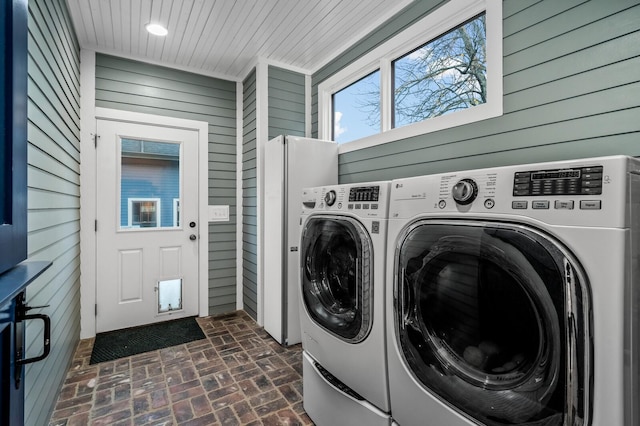 clothes washing area with wooden walls and separate washer and dryer