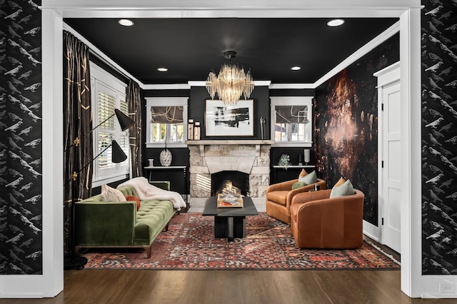 living room with an inviting chandelier, crown molding, a fireplace, and dark hardwood / wood-style floors