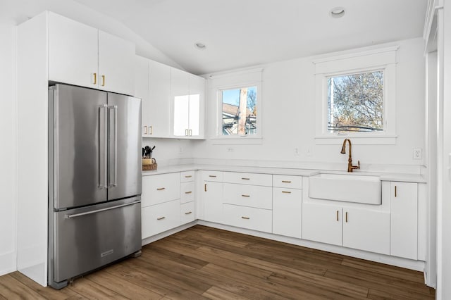 kitchen with white cabinets, vaulted ceiling, dark hardwood / wood-style flooring, sink, and high end fridge