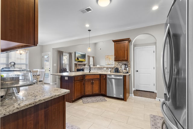 kitchen featuring light stone counters, appliances with stainless steel finishes, backsplash, and sink