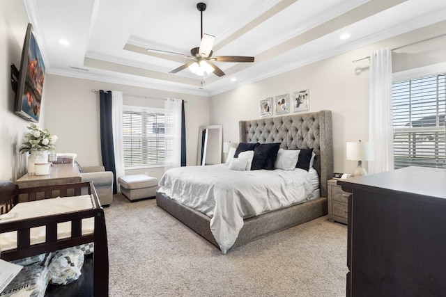 bedroom with ceiling fan, a tray ceiling, crown molding, and light carpet