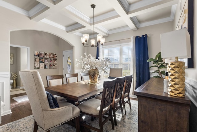 dining space with an inviting chandelier, beamed ceiling, ornamental molding, wood-type flooring, and coffered ceiling