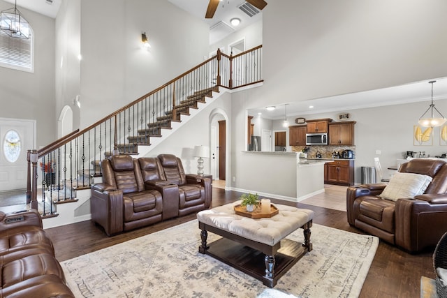 living room featuring a towering ceiling, dark hardwood / wood-style flooring, and ceiling fan with notable chandelier