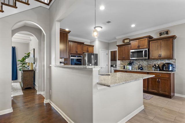 kitchen featuring light stone countertops, light hardwood / wood-style flooring, stainless steel appliances, decorative backsplash, and ornamental molding