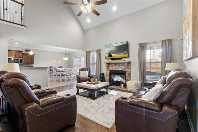 living room featuring high vaulted ceiling, a fireplace, ceiling fan, and dark wood-type flooring