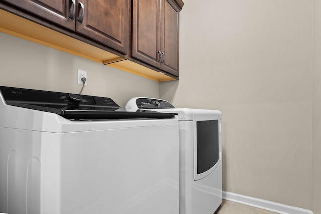 clothes washing area with cabinets and washing machine and clothes dryer