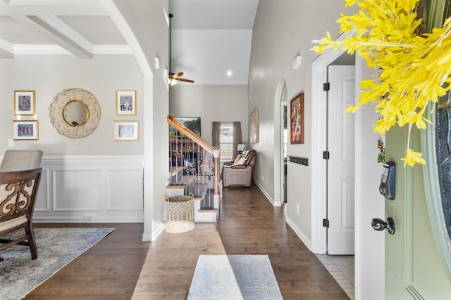 foyer with dark wood-type flooring, beam ceiling, ceiling fan, and ornamental molding