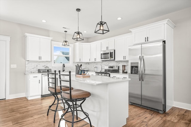 kitchen featuring decorative backsplash, light wood-style floors, appliances with stainless steel finishes, and white cabinetry