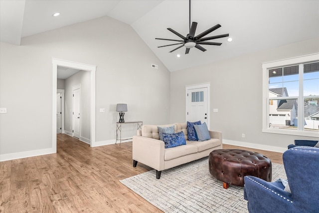 living area featuring a ceiling fan, visible vents, baseboards, high vaulted ceiling, and light wood-type flooring