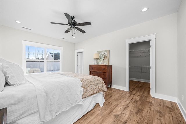 bedroom featuring visible vents, wood finished floors, recessed lighting, baseboards, and a spacious closet