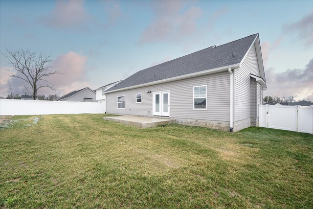 back of property with a shingled roof, a fenced backyard, a yard, a patio, and a gate