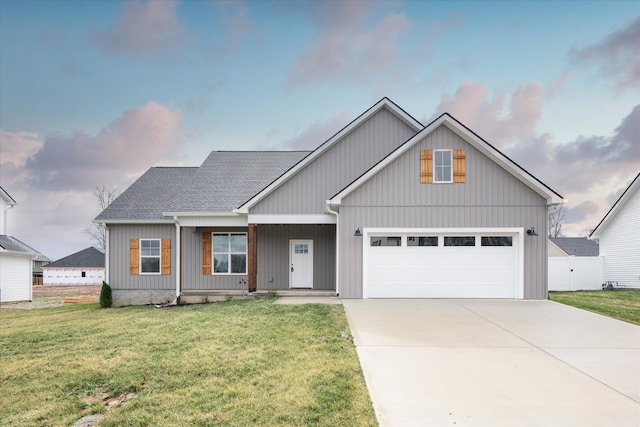 view of front facade featuring an attached garage, concrete driveway, a front lawn, and a shingled roof