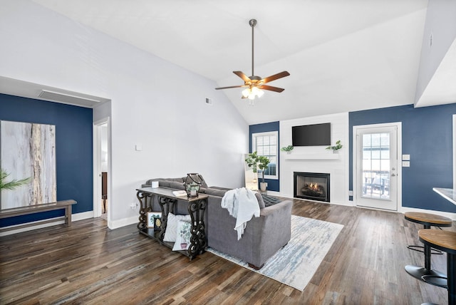 living room featuring a fireplace, dark wood-type flooring, ceiling fan, and vaulted ceiling