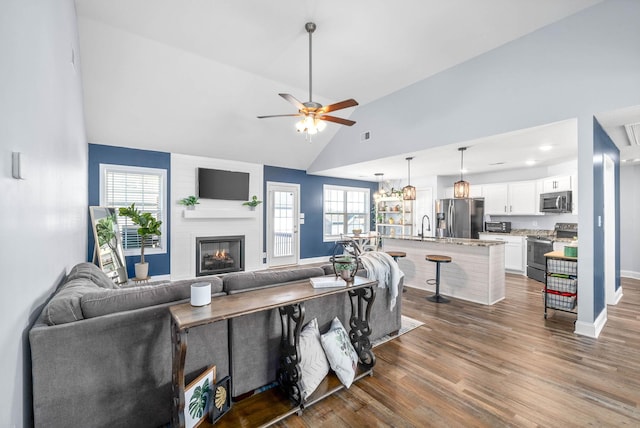 living room featuring ceiling fan, a wealth of natural light, a fireplace, and dark hardwood / wood-style floors