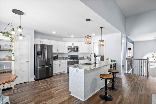 kitchen featuring appliances with stainless steel finishes, stone counters, pendant lighting, white cabinets, and sink