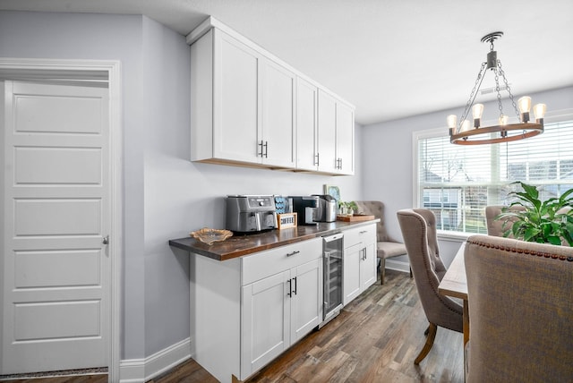 bar featuring white cabinetry, butcher block counters, beverage cooler, a chandelier, and pendant lighting