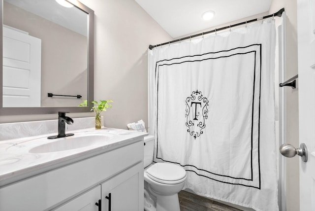 bathroom with hardwood / wood-style flooring, toilet, vanity, and walk in shower