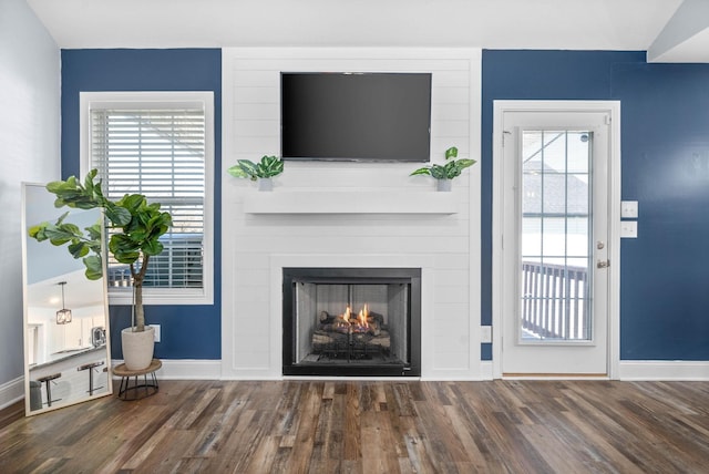 living room featuring dark wood-type flooring and a large fireplace