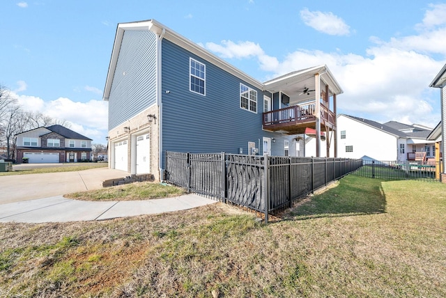 back of property featuring a balcony, ceiling fan, a garage, and a lawn