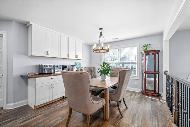 dining space with dark wood-type flooring and a notable chandelier