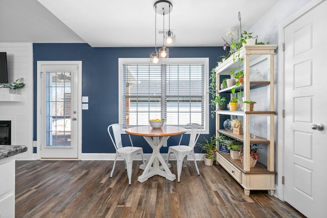 dining room with dark wood-type flooring and a fireplace