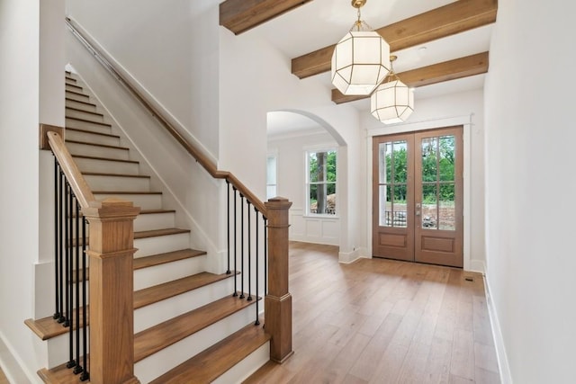 entrance foyer with beam ceiling, french doors, and light hardwood / wood-style flooring