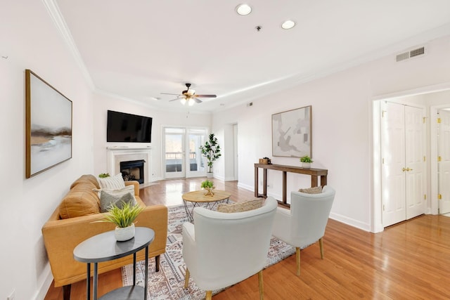 living room featuring wood-type flooring, ceiling fan, and crown molding