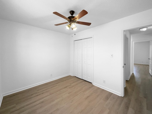 unfurnished bedroom with hardwood / wood-style flooring, a textured ceiling, ceiling fan, and a closet