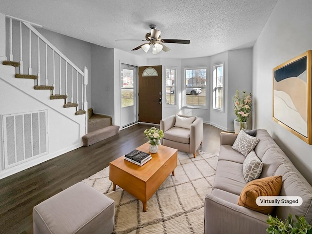 living room with a textured ceiling, ceiling fan, and wood-type flooring