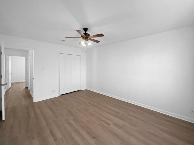 unfurnished bedroom with a closet, ceiling fan, and dark wood-type flooring