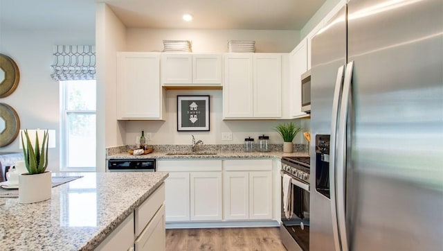 kitchen with stainless steel appliances, white cabinets, sink, and light stone counters