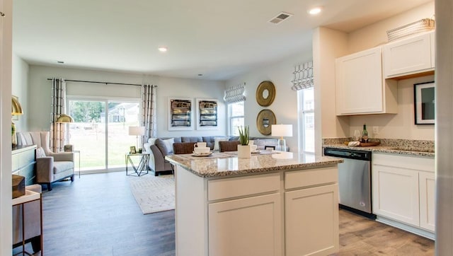 kitchen with stainless steel dishwasher, white cabinetry, a center island, and light hardwood / wood-style flooring