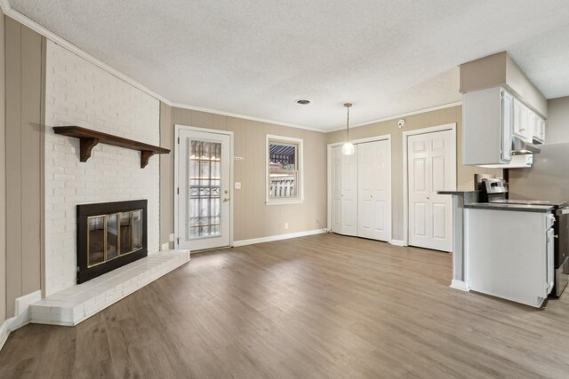 interior space featuring a brick fireplace, ornamental molding, a healthy amount of sunlight, and light hardwood / wood-style floors