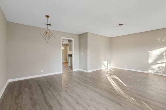 unfurnished room with a textured ceiling and hardwood / wood-style floors